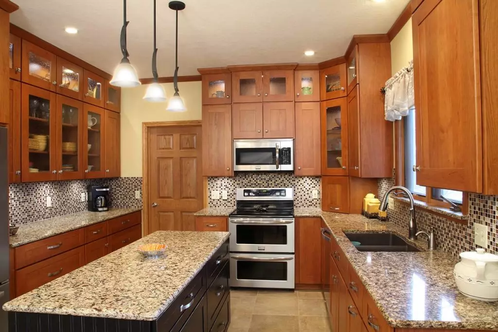 A wide view of a remodeled kitchen featuring refaced warm cherry cabinets.