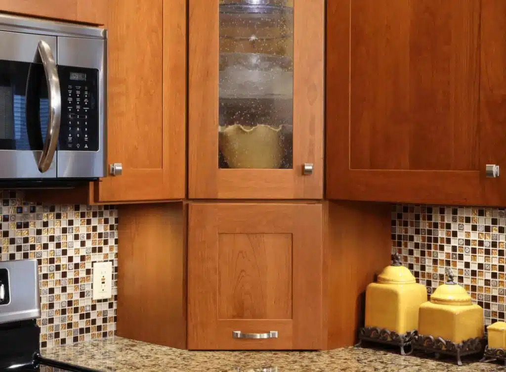 Close-up of wooden kitchen hardware with metallic handles and a granite countertop.