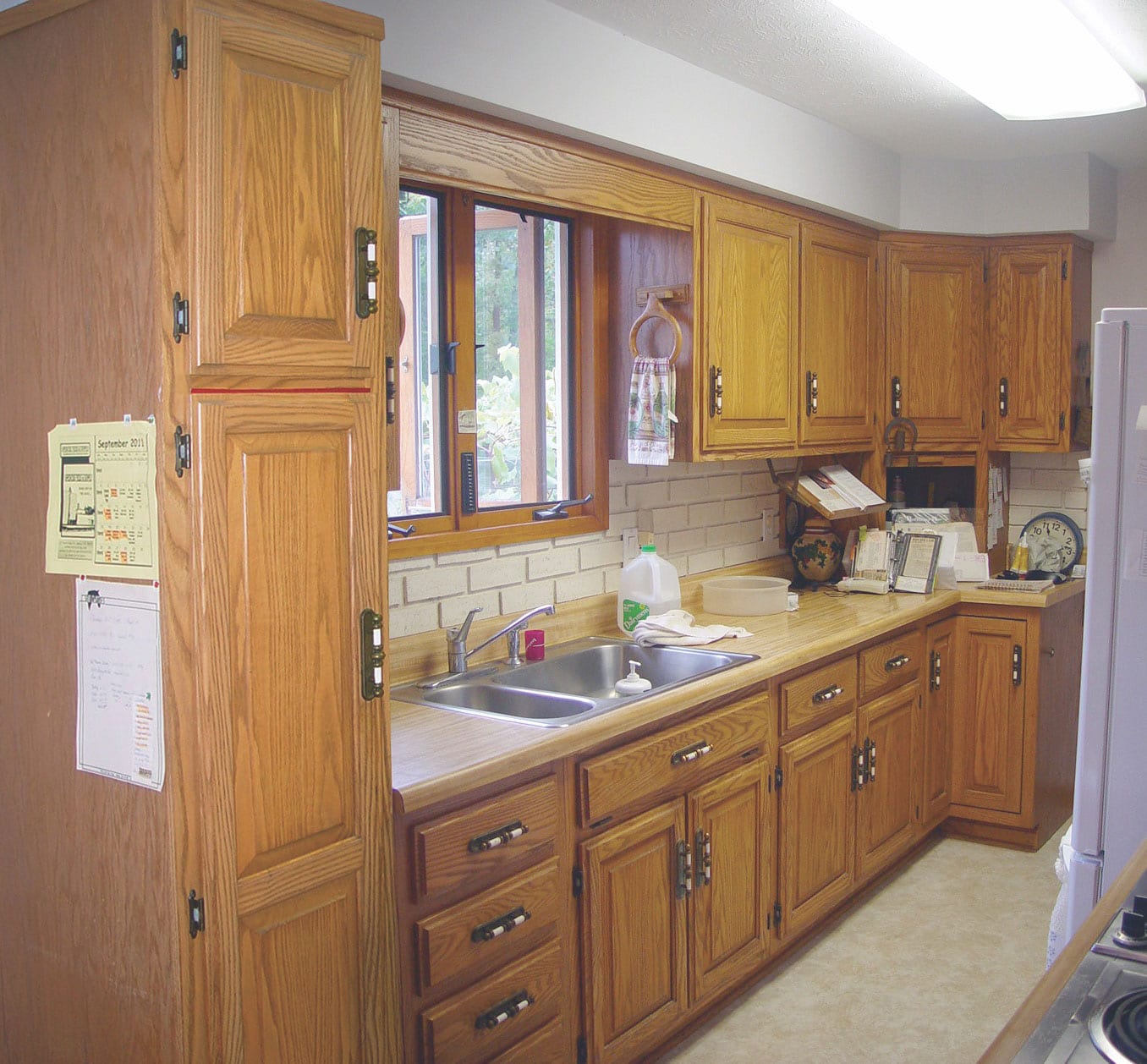 a picture of an old kitchen and brown cabinets made from wood and the cabinets not extend to the ceiling