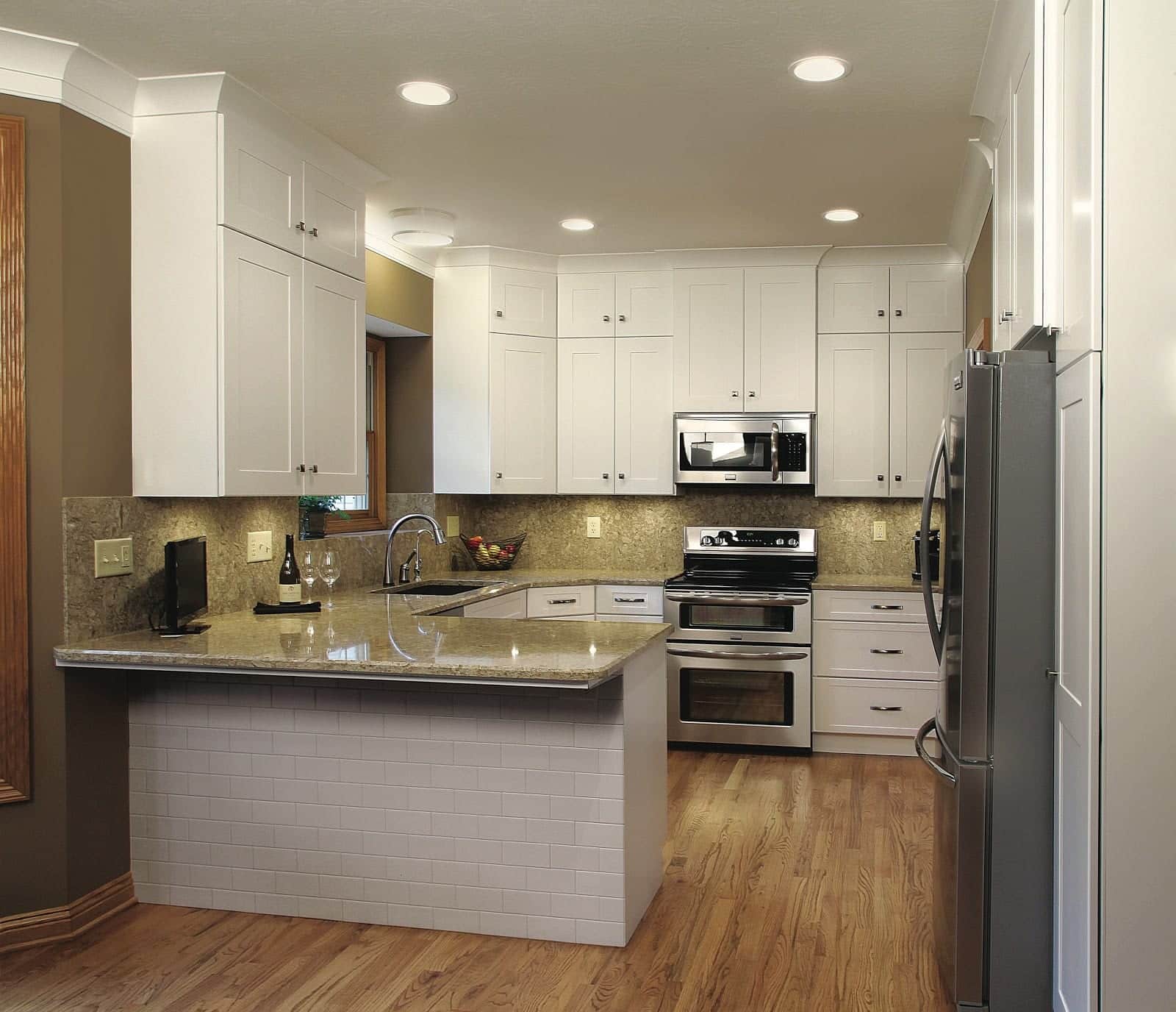 a picture of the kitchen after refacing featuring a white cabinet extended to the ceiling and will cornered countertop and proper placement of the appliances