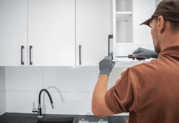 Worker finishing the installment of cabinet in the kitchen area.