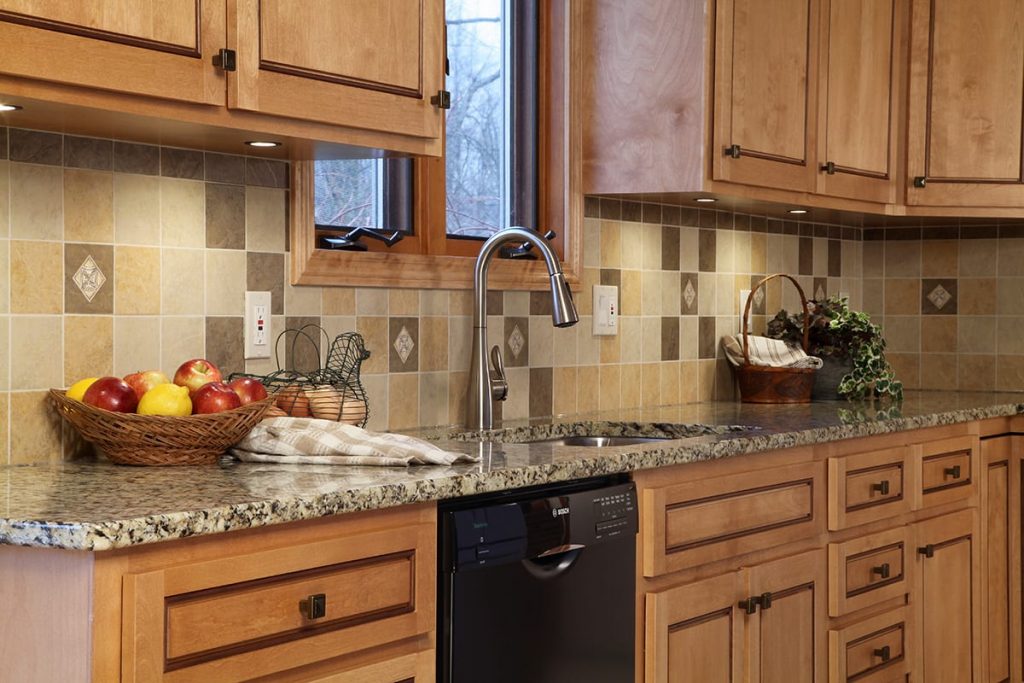 Close-up view of a gray sink run in a kitchen, with white countertops, stainless steel faucet, and modern light fixtures.