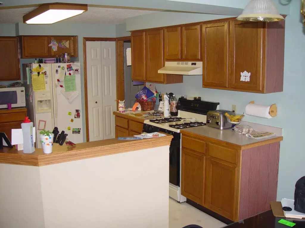 An outdated kitchen with worn wooden cabinets