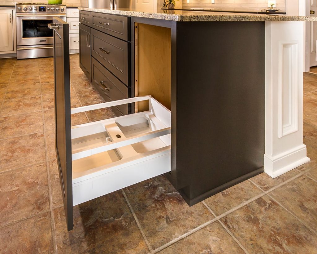 Contemporary kitchen with kitchen island featuring a pull-out trash bin cabinet