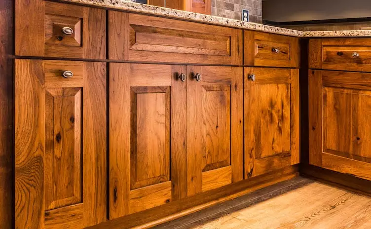 Close-up of rustic, heavily grained wood refaced cabinets with a granite countertop.
