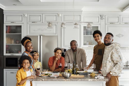 Happy African family posing around the center island in their white comfy kitchen - Functional Kitchen Cabinet Ideas