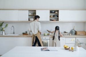 man and little girl in a all white kitchen cooking - how long do refaced cabinets last?
