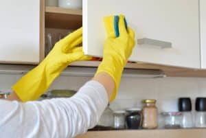 Cleaner using a hot water and sponge to clean the cabinet door in the kitchen