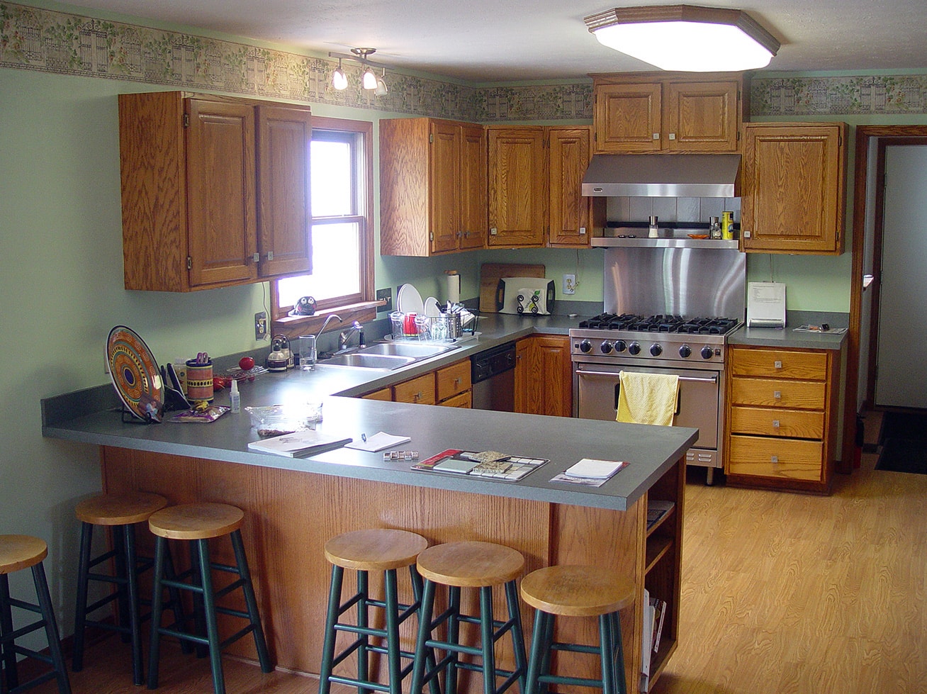 Image of a Kitchen with white cabinets and a blue backsplash. The countertop is made of white granite with gray veining. The backsplash has a hexagonal pattern in shades of blue. There is a white range hood above a stainless steel range, and a sink with a chrome faucet is visible in the foreground.