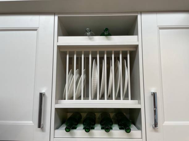 Kitchen cabinet with a dish rack and wine rack full of white dinner plates and wine bottles.