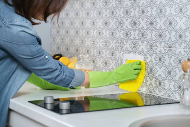 Woman in gloves cleaning the kitchen area in her house.