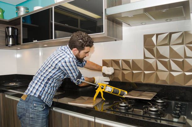 Man installing tile on his kitchen backsplash.