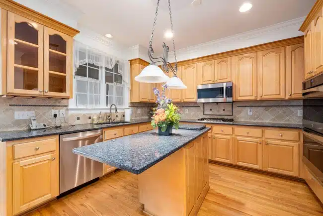 Kitchen Design with Wooden Cabinets and Marble Top Counters.