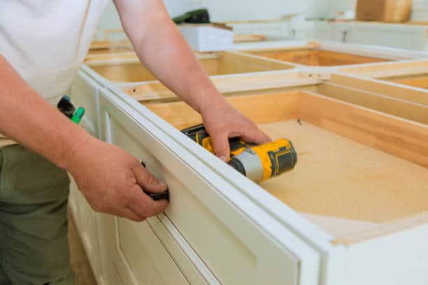 Man doing some DIY kitchen cabinet refacing on his kitchen.