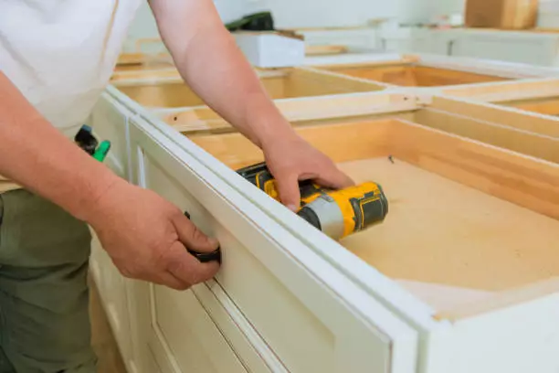 Man doing some DIY kitchen cabinet refacing on his kitchen.