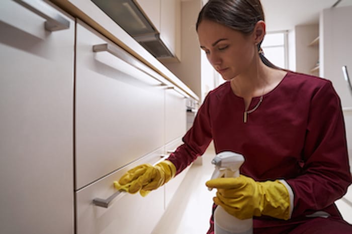 woman using the right cleaning product to extend the lifespan of refaced cabinets