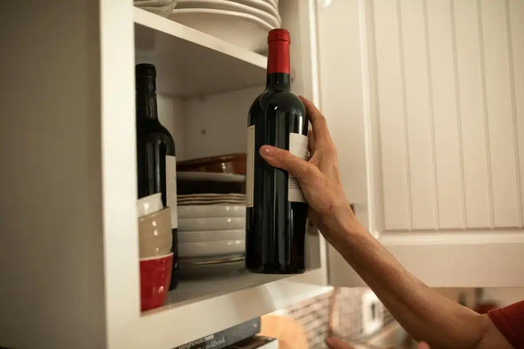 Person Holding Black Glass Bottle